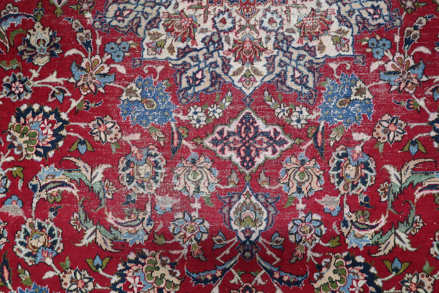 Detail of the wide ivory border on a 1900s Tabriz carpet, featuring classic scrolling vines and floral sprays.

