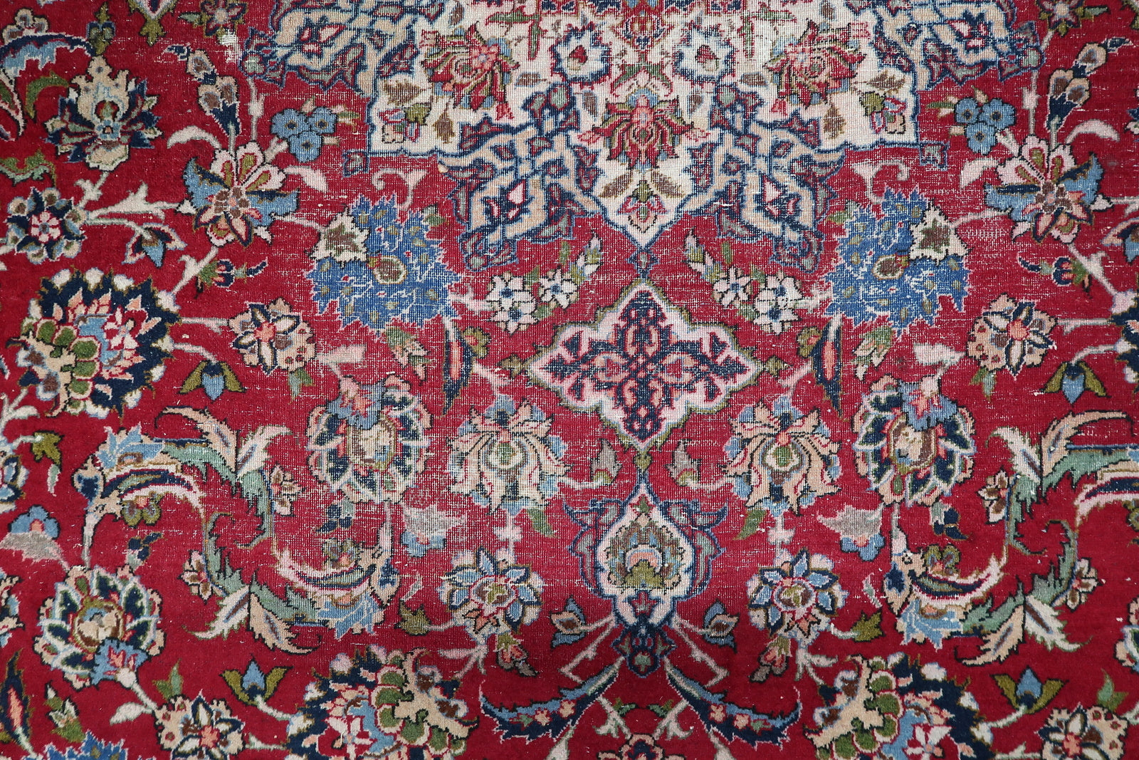 Detail of the wide ivory border on a 1900s Tabriz carpet, featuring classic scrolling vines and floral sprays.

