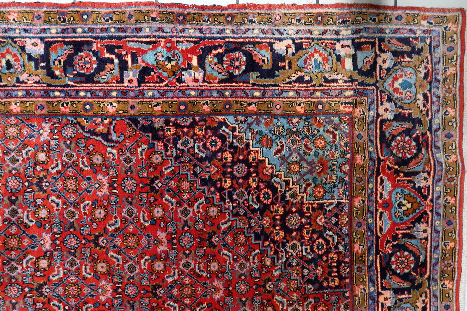 Handmade Persian carpet circa 1920, showcasing a traditional Herati (mahi) motif densely populating the field around the ornate central focal point.

