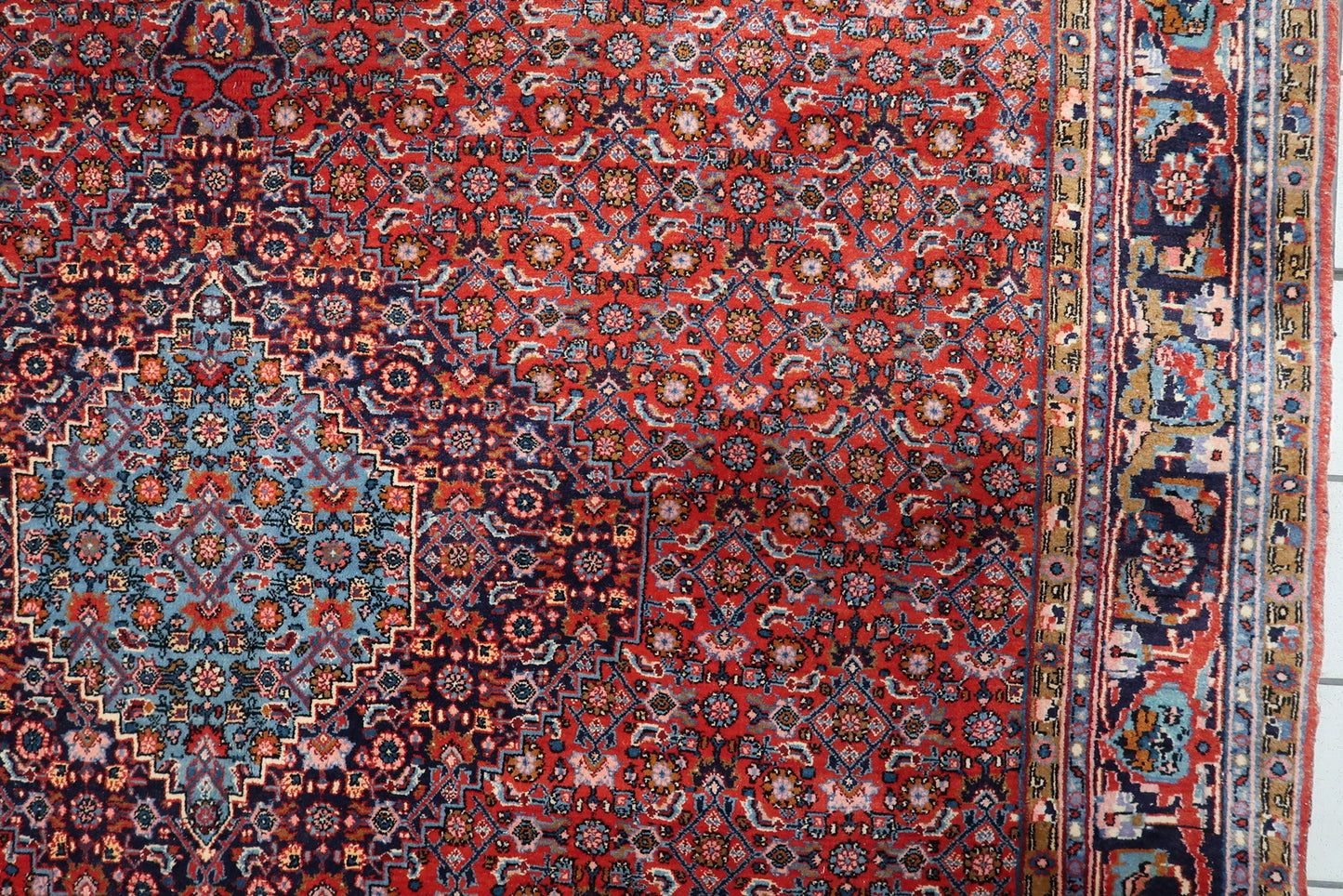 Complex multi-layered border of a Persian Bidjar rug, featuring midnight blue and ochre accents framing the composition.

