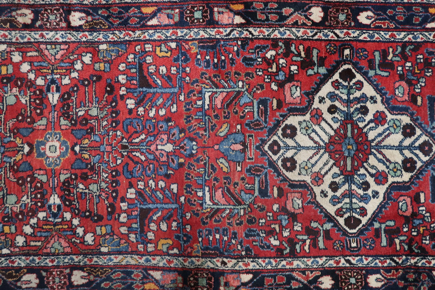 Long vintage rug with triple medallion design, featuring surface wear that contributes to its antique charm and authenticity.

