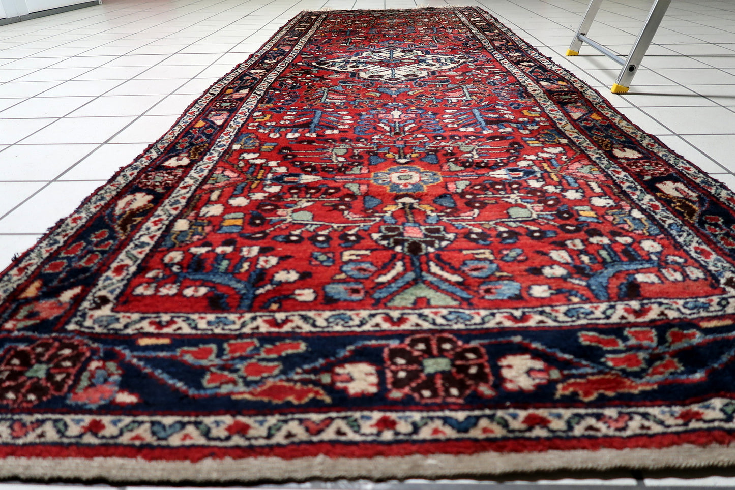 Midnight blue border framing the composition of an antique Hamadan runner, contrasting with the deep red field.


