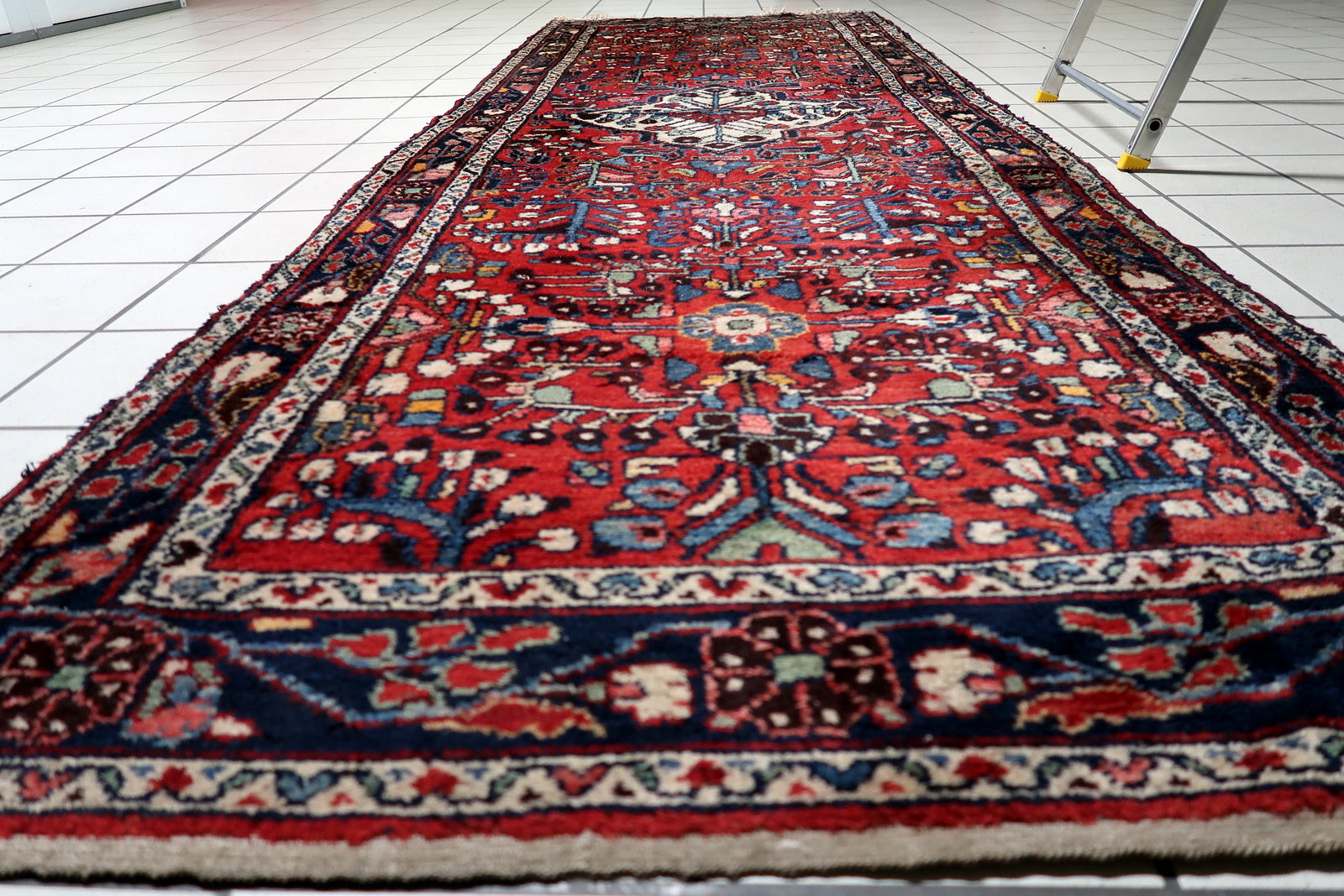 Midnight blue border framing the composition of an antique Hamadan runner, contrasting with the deep red field.

