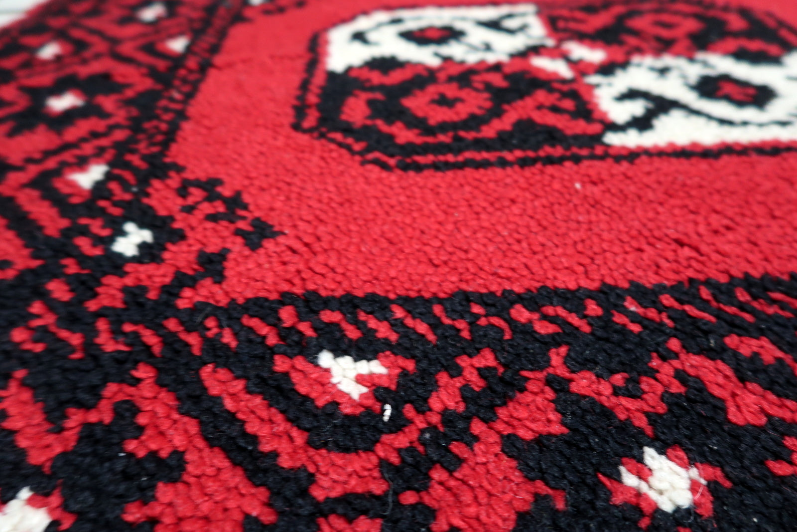 Color palette close-up of a 1950s rug: vibrant scarlet red, jet black, and cream in a striking graphic composition.

