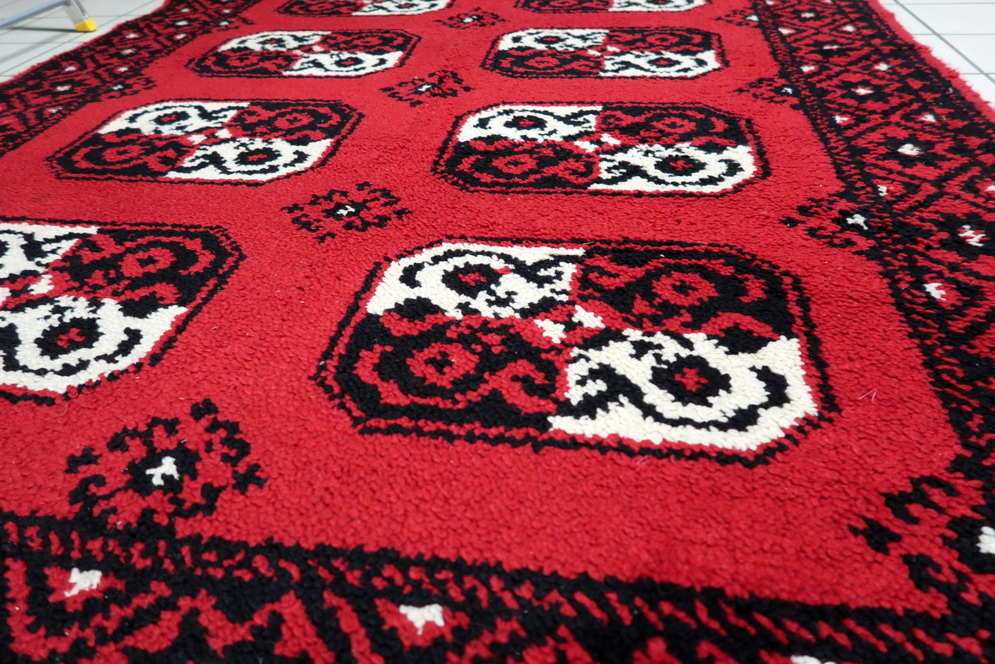 A graphic 1950s carpet with octagonal guls, perfect for adding a pop of scarlet red and geometric order to a minimalist interior.

