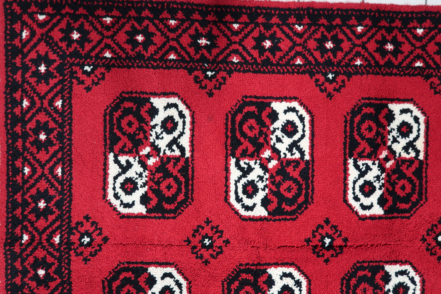 Detail showing two vertical rows of five repeating geometric medallions creating ordered symmetry on a 1950s Savonnerie-style carpet.

