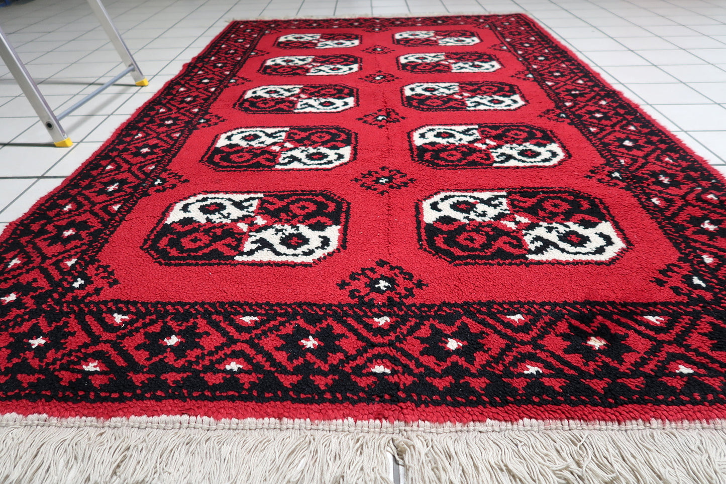 Texture detail of the dense, plush wool pile on a vintage French rug, demonstrating its luxurious quality and vibrant scarlet color.


