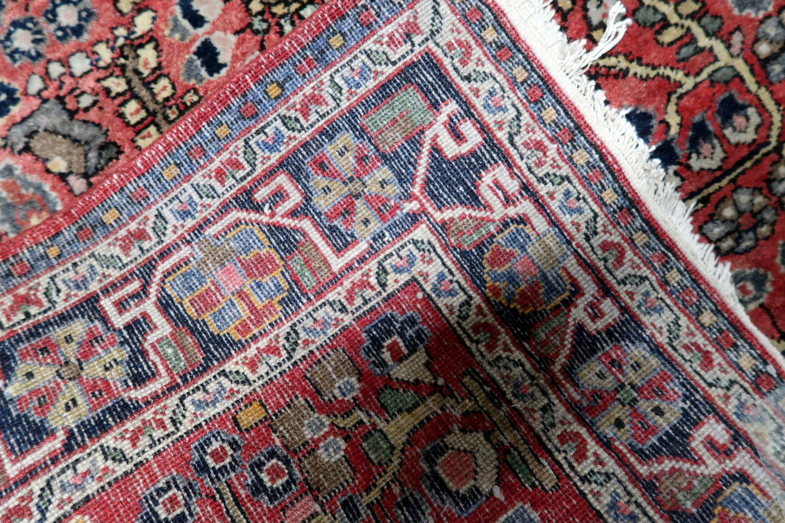 Sophisticated color palette detail: madder red, midnight blue, ivory, and soft earth tones on a vintage Hamadan rug.

