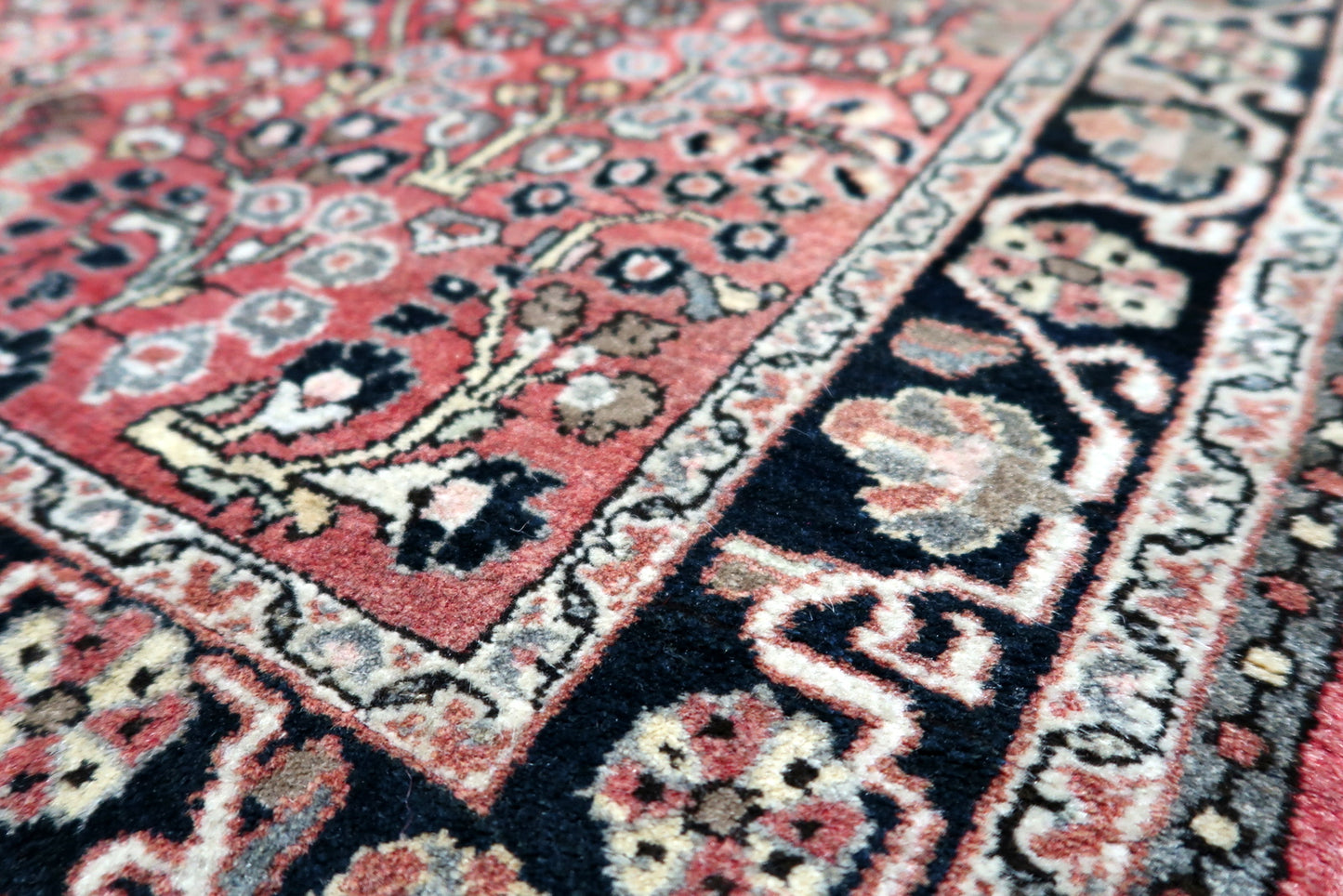 A 1950s hand-knotted rug with an all-over floral design, ideal for placing in a classic study or as a bedside accent in a bedroom.

