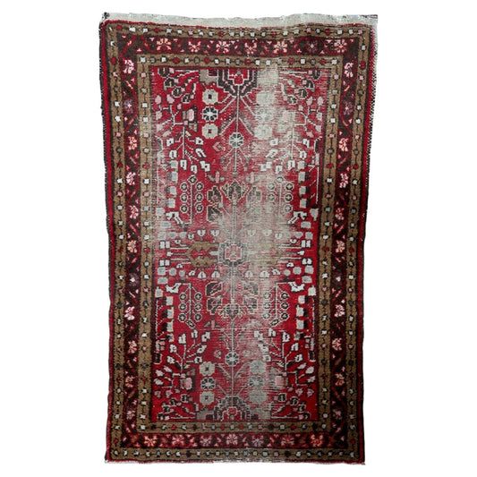 Antique distressed Persian Hamadan rug from the 1920s, hand-knotted wool on cotton, featuring stylized geometric and floral motifs. 77 x 133 cm.

