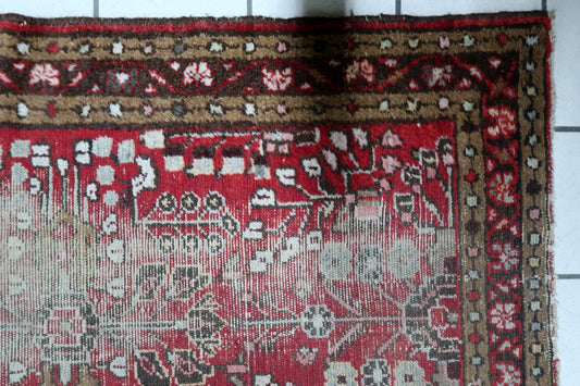 Early 20th century Persian village rug with a deep crimson field and weathered beauty, showcasing significant areas of low pile. 2'6" x 4'4".

