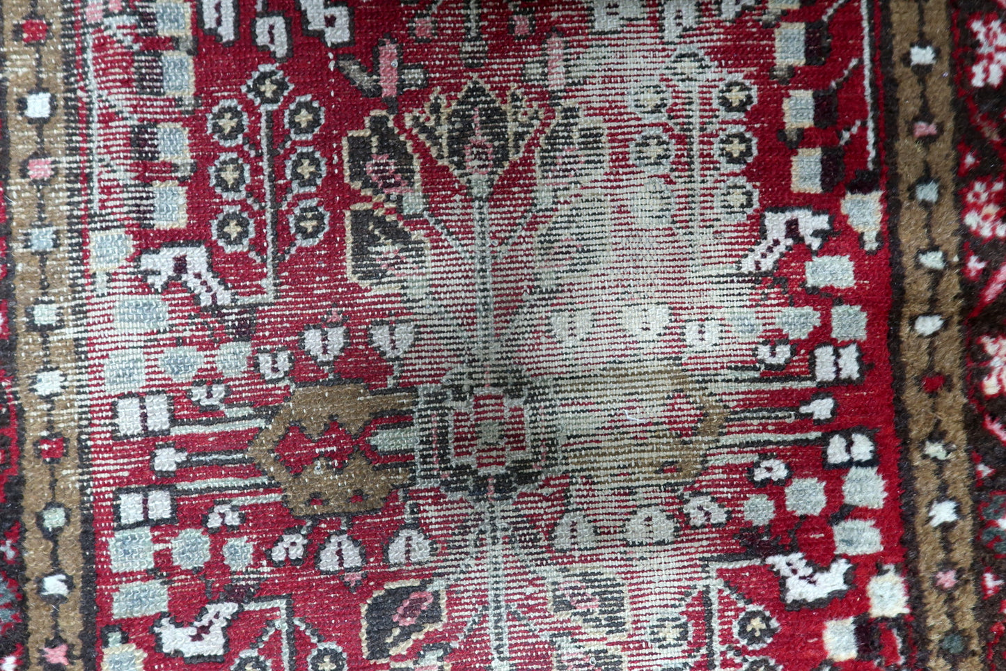 Detail of the distressed aesthetic on an antique rug, showing visible wear and low-to-absent pile that reveals the structural soul.

