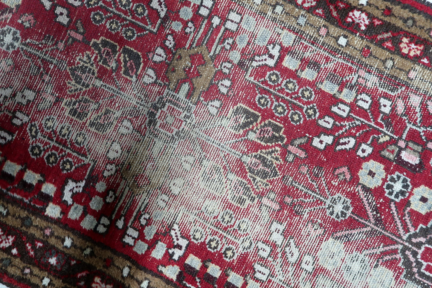 The triple-border design of an antique Hamadan rug, rendered in earthy browns, creams, and reds, perfectly containing the energetic central field.

