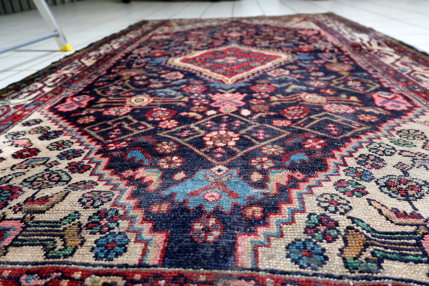Dense array of stylized floral and geometric tribal motifs surrounding the central medallion on an antique Persian Hamadan.

