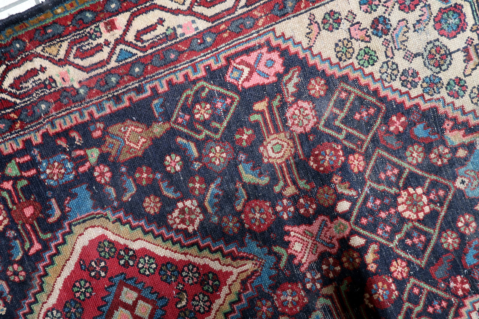 Close-up of the vibrant red and sky-blue central diamond medallion anchoring the deep indigo-blue field of a 1920s Hamadan rug.

