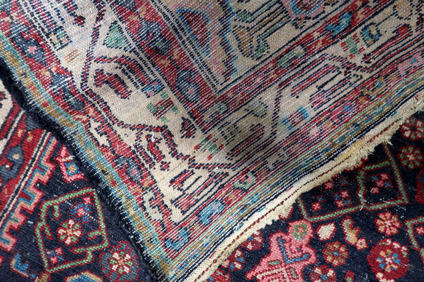 Texture close-up of hand-spun wool aged beautifully on a 100-year-old rug, showing areas of low pile that add sought-after character.

