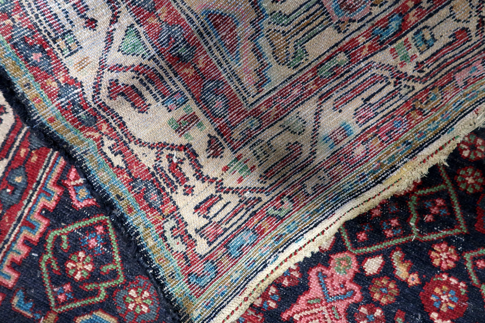 Texture close-up of hand-spun wool aged beautifully on a 100-year-old rug, showing areas of low pile that add sought-after character.

