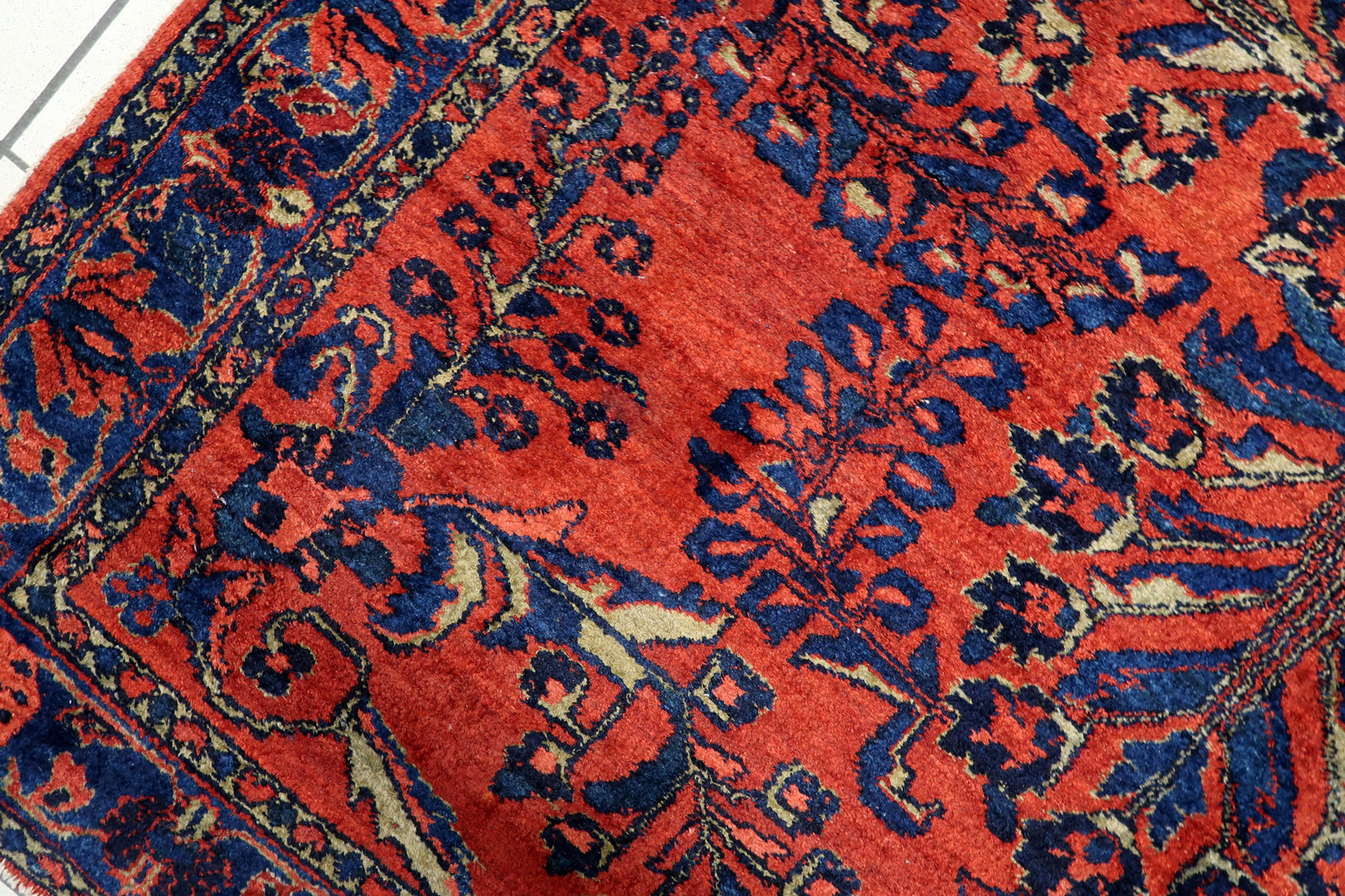 Close-up of the large-scale symmetrical floral design on a 1920s Persian Lilihan rug, featuring blossoming branches and stylized floral sprays.


