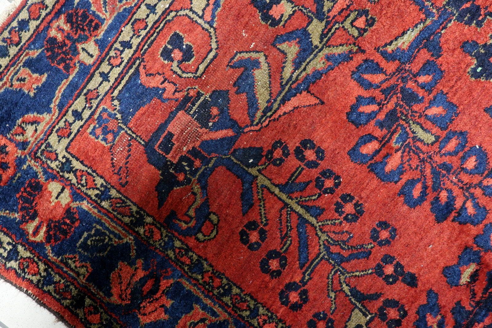 Texture close-up of high-quality, lustrous wool on a 100-year-old rug, showing subtle age-related wear that adds authentic vintage charm.

