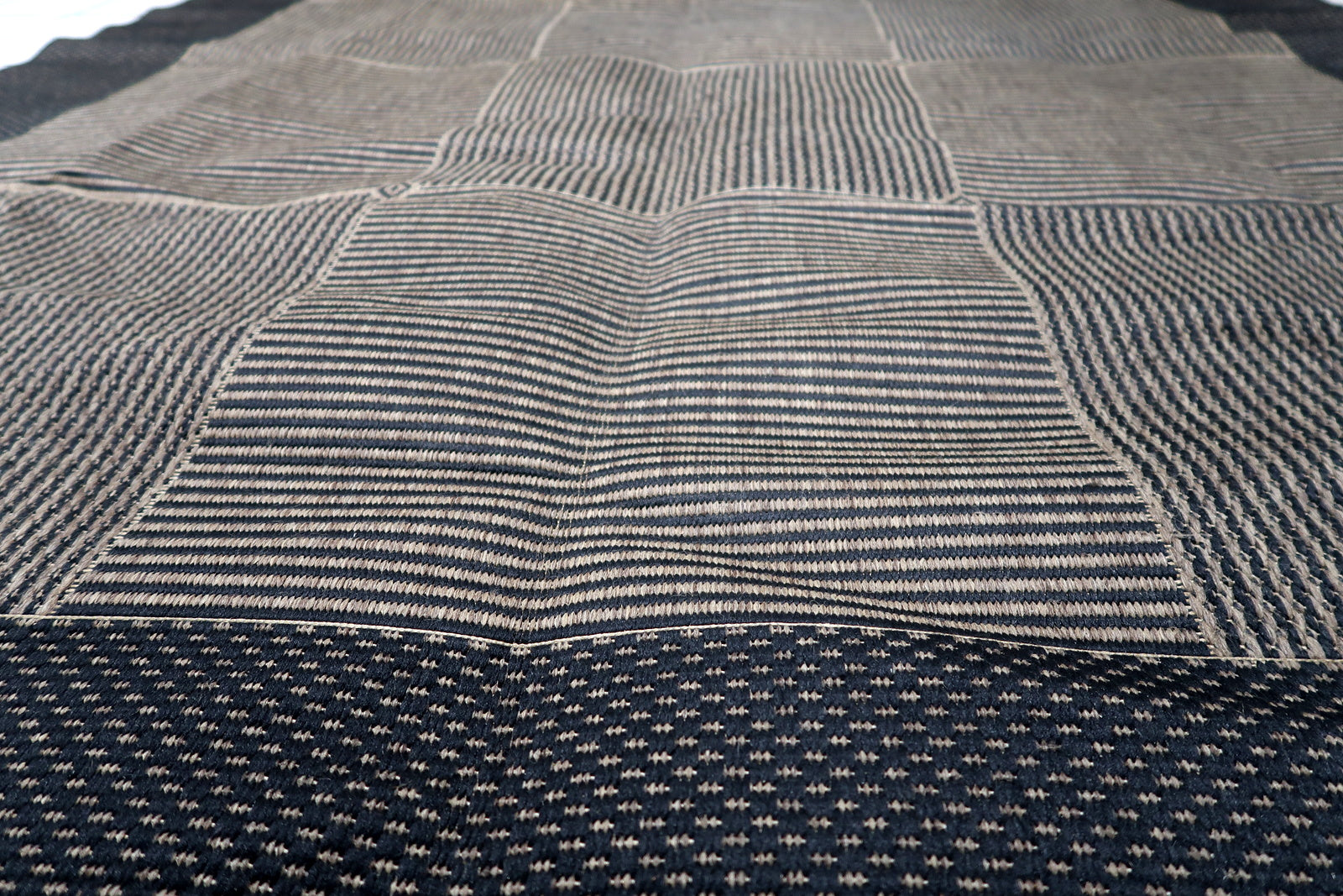 Machine-woven geometric carpet in charcoal and taupe, perfect for adding a touch of retro-European cool to modern interiors.

