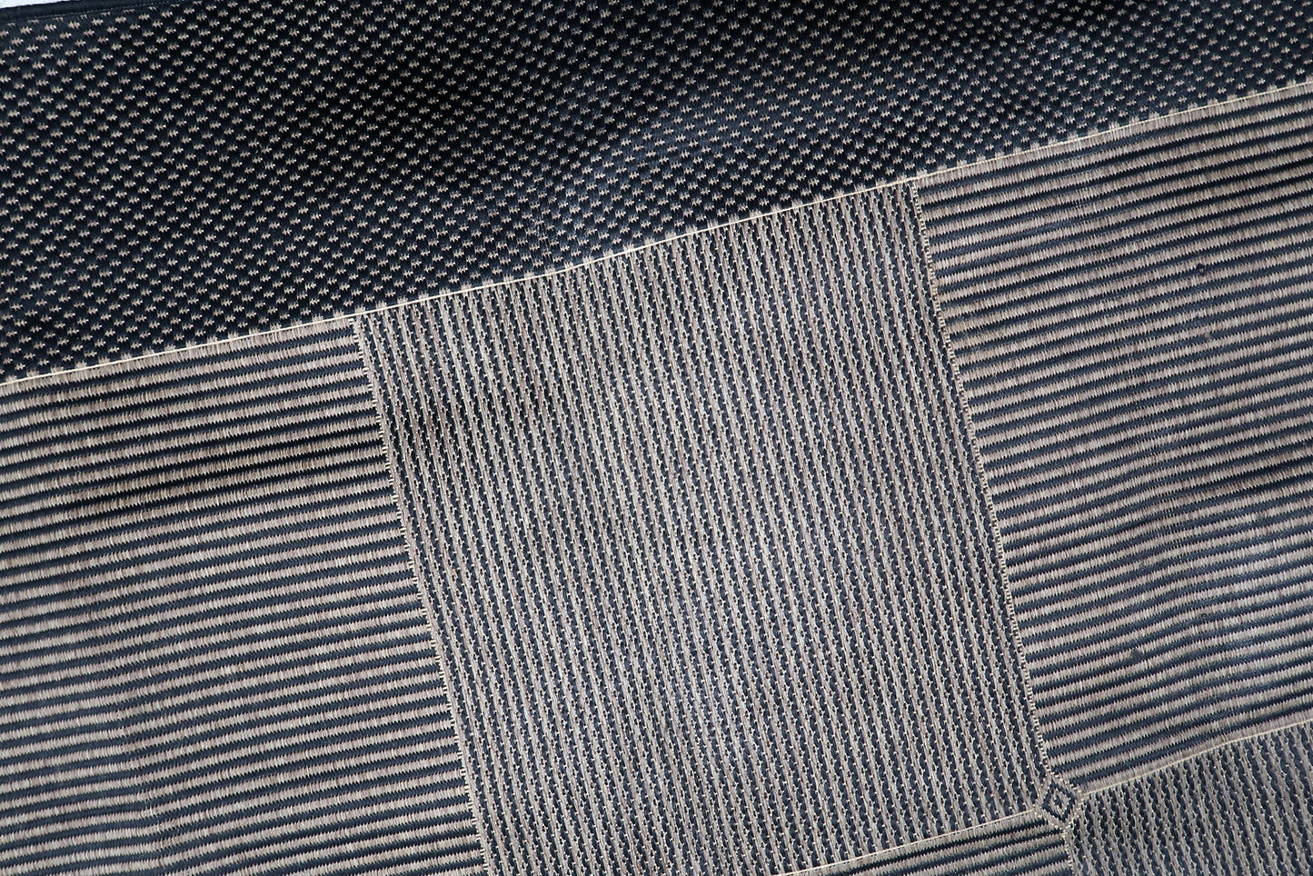 Machine-made vintage rug from the 1980s, perfect for high-traffic modern spaces, with a wide pebbled charcoal border anchoring the geometric interior.

