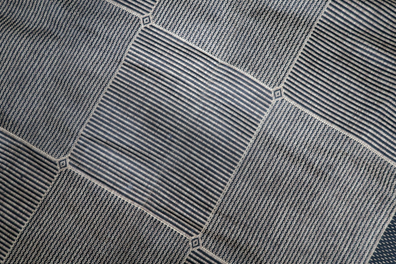 Close-up of the sophisticated grid pattern on a 1980s Belgian rug, featuring alternating textured squares in a monochromatic grey and taupe palette.

