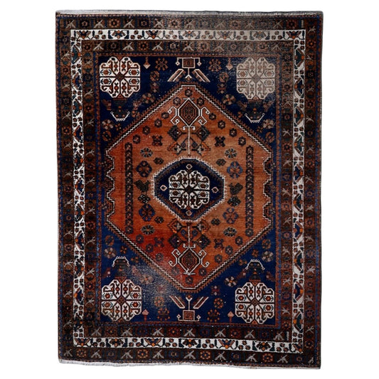 Antique Shiraz Gashkai rug from the 1920s, hand-knotted wool, featuring an elongated terracotta-orange hexagonal medallion on a deep midnight-blue field. 155 x 207 cm.


