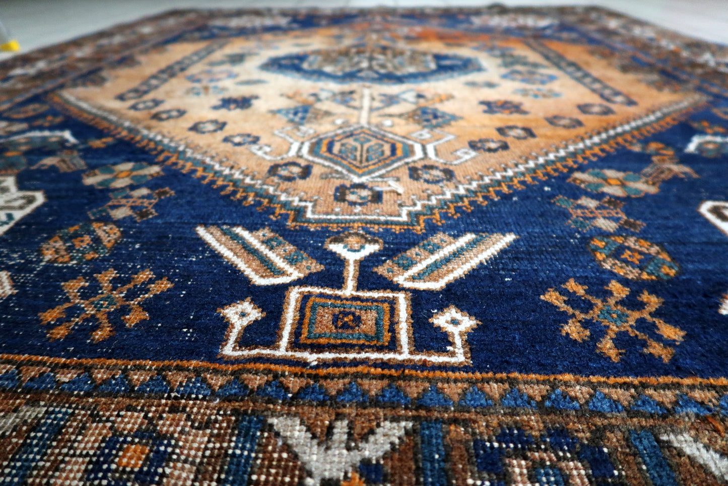 Deep midnight-blue and terracotta-orange antique rug complementing both minimalist and eclectic decor styles.

