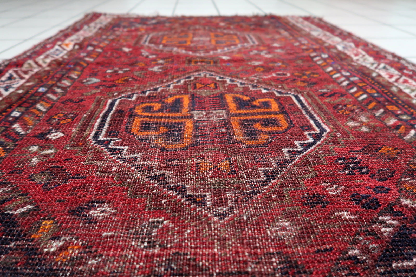 Distressed Persian rug with significant age-wear, adding a sense of history and warmth to a contemporary loft or minimalist space.


