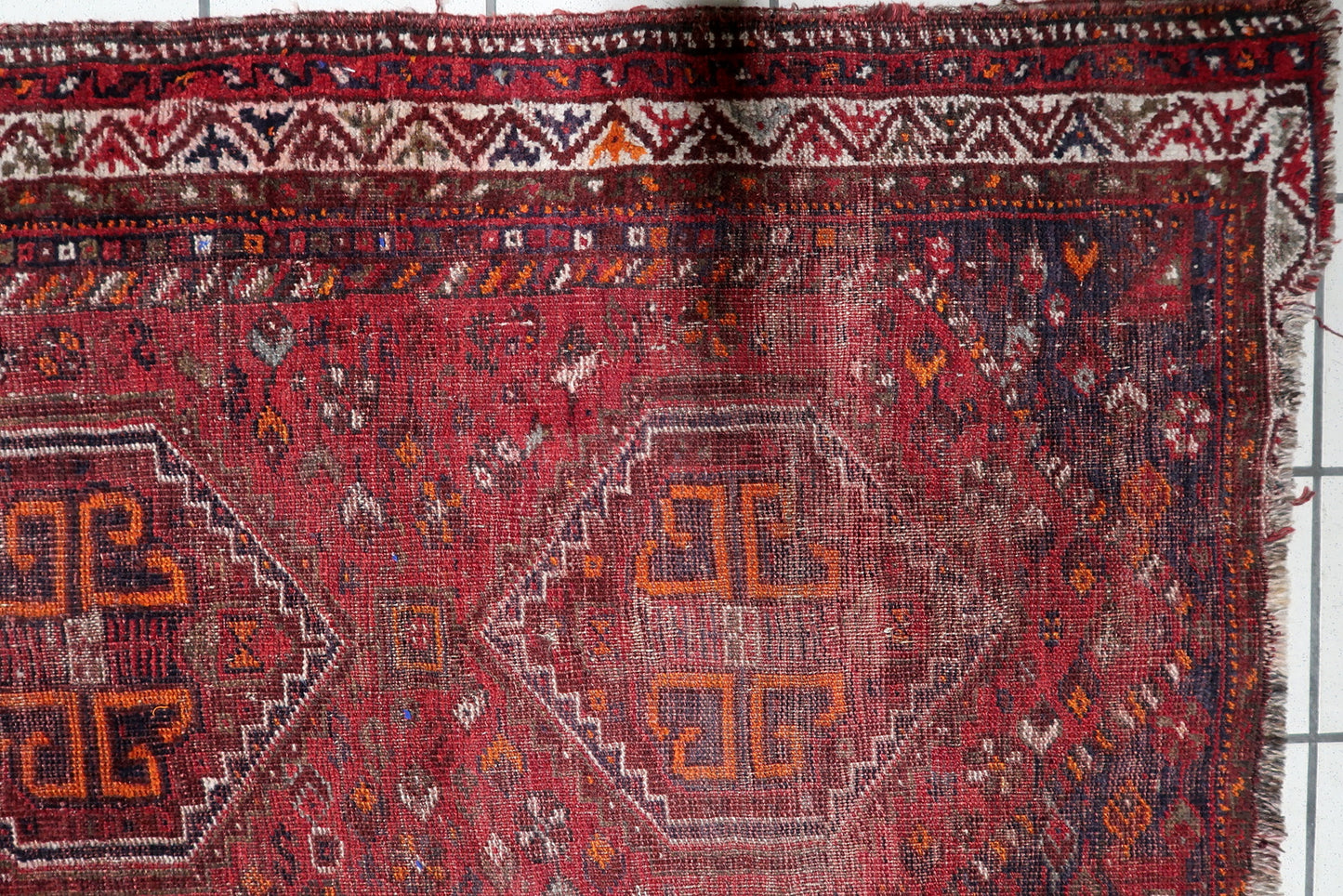 Detail of the densely packed field of nomadic ornaments on an antique South Persian rug, including stars and protective "eye" motifs.

