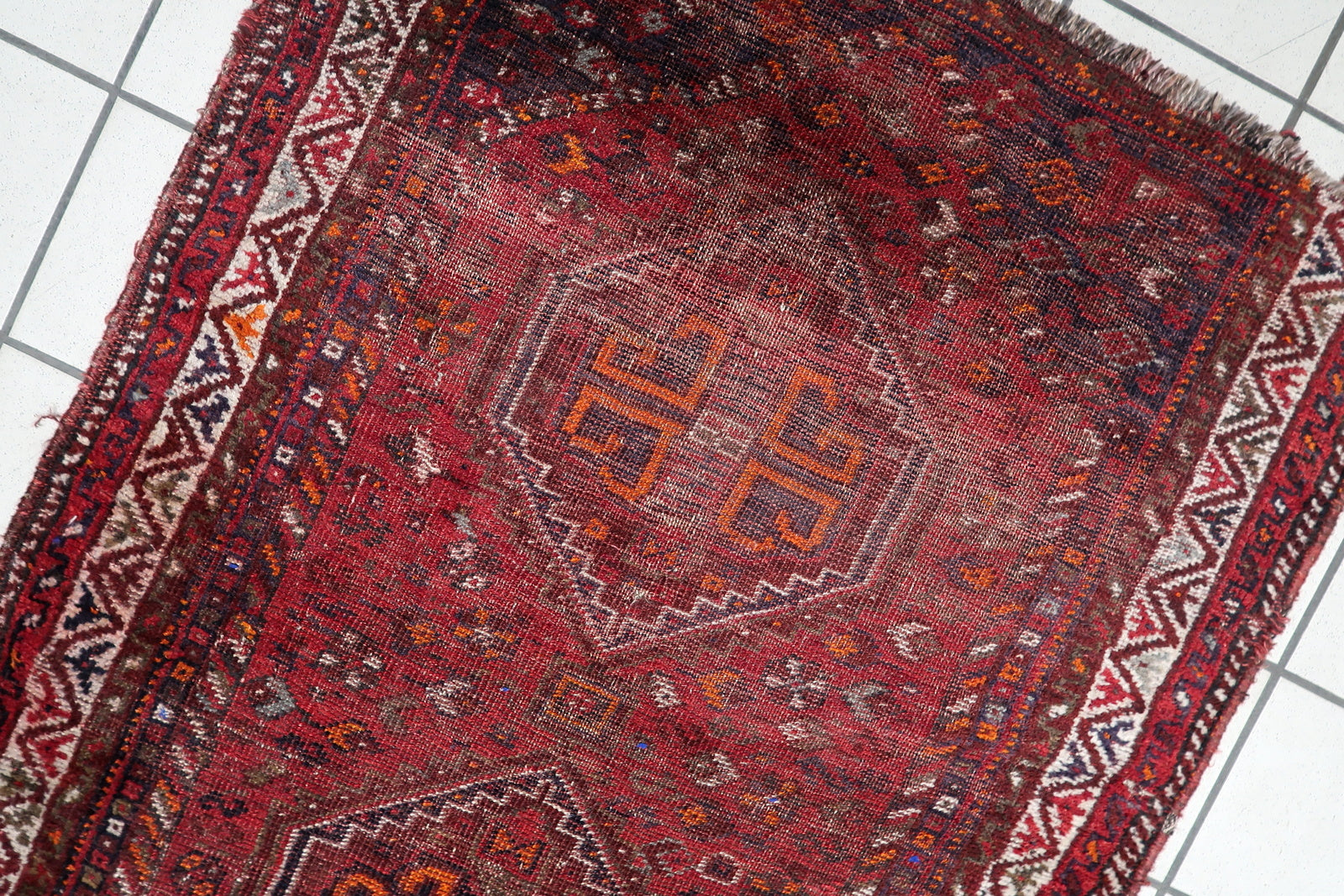 Antique Persian Shiraz rug with rugged, weathered character, ideal for grounding a modern interior with an authentic piece of tribal art.

