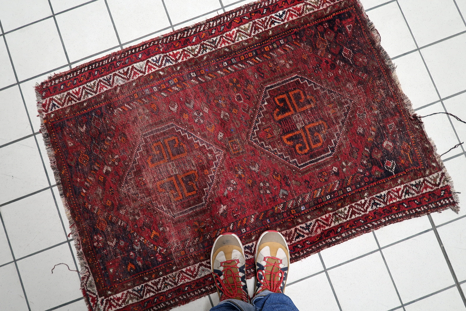 A 1900s nomadic tribal carpet with low, textured surface, perfect for collectors seeking a soulful, century-old artifact.

