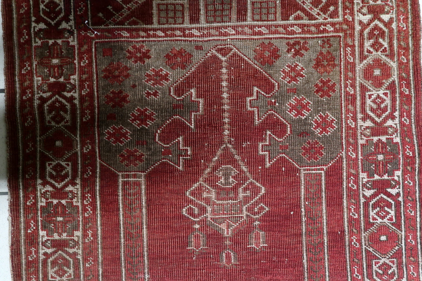 Small antique Turkish prayer rug (80 cm x 107 cm) with a classical repeating geometric chain border in cream and red, framing the spiritual composition.

