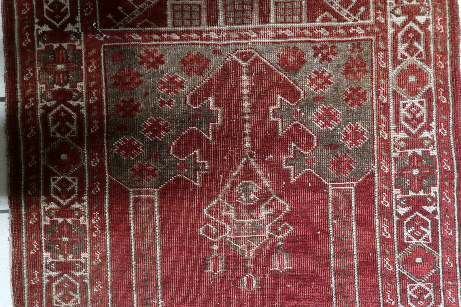 Small antique Turkish prayer rug (80 cm x 107 cm) with a classical repeating geometric chain border in cream and red, framing the spiritual composition.

