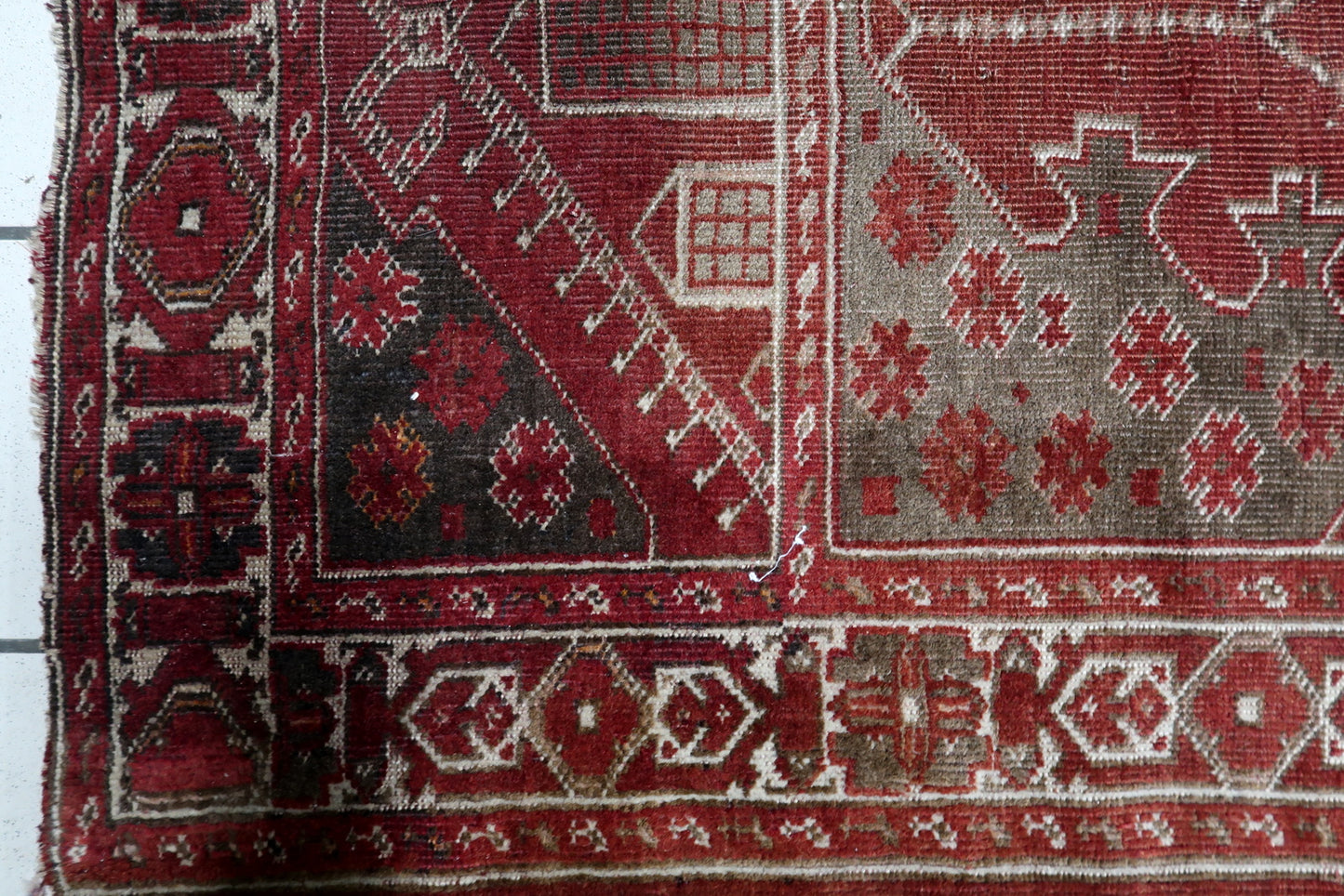 Close-up of the warm madder-red mihrab field on a 1920s Turkish Konya rug, containing a central stylized "Tree of Life" or floral pillar motif.


