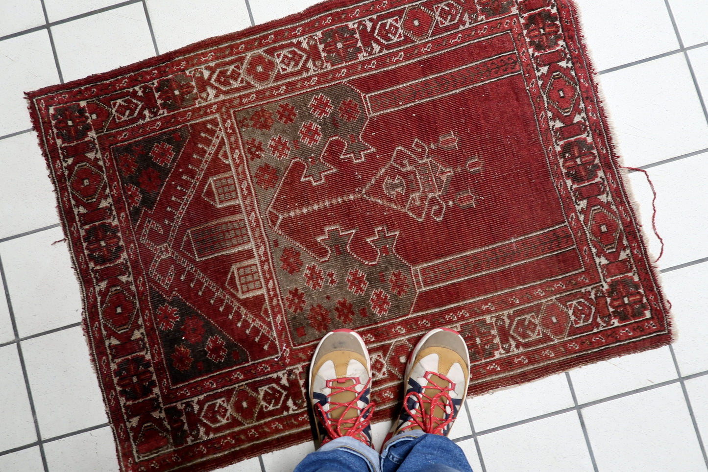The deep charcoal-brown upper spandrels of an antique Konya rug, decorated with vibrant red blossoms that contrast with the earthy lower section.

