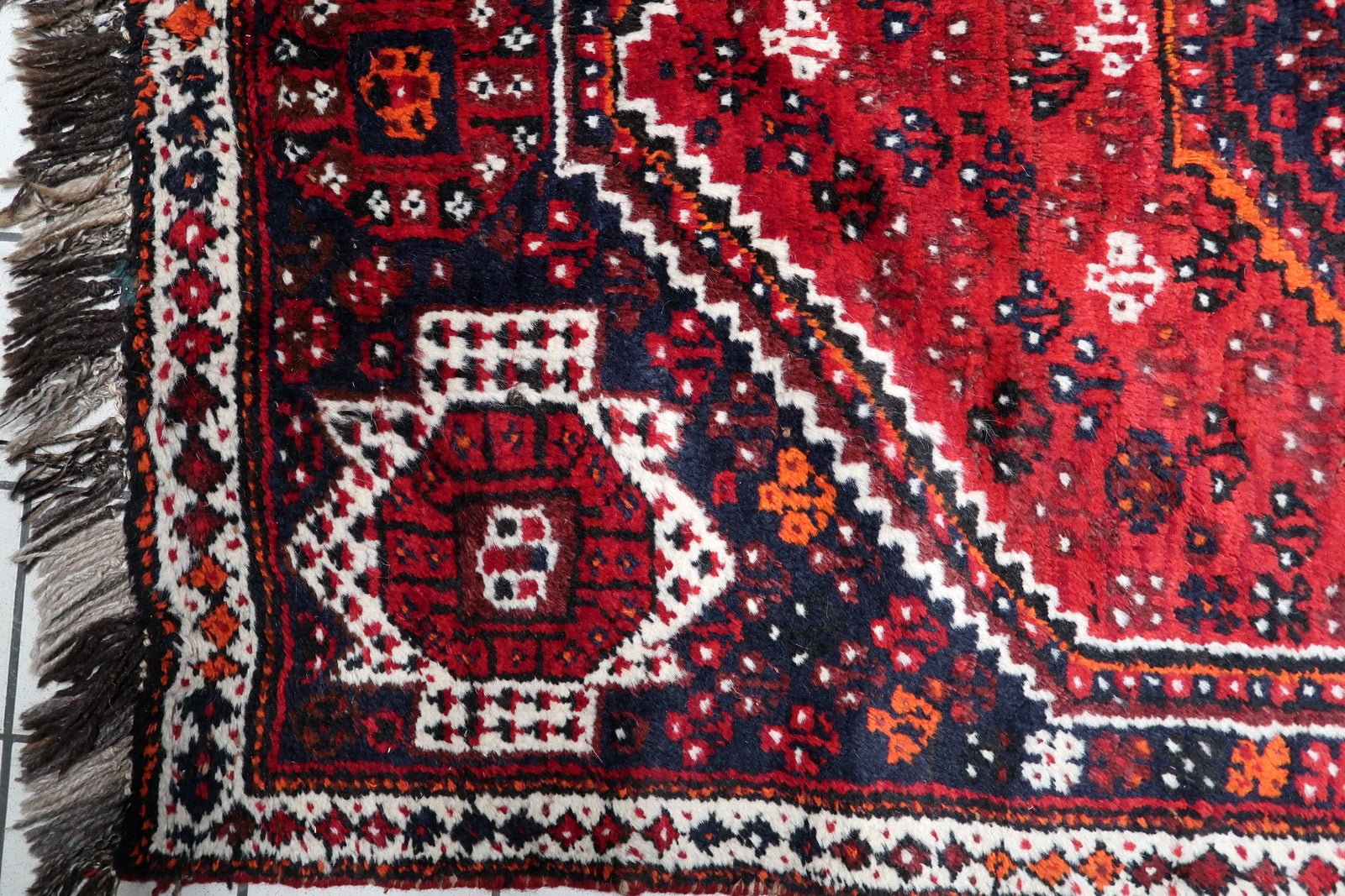 Hand-spun wool texture close-up of an antique South Persian tribal rug from the Shiraz region.

