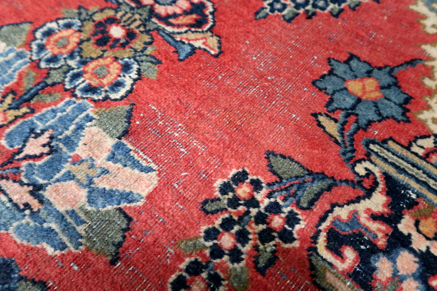 Lustrous wool pile texture of an antique Persian Kashan rug displaying a rich palette of midnight blue, ivory, rose, and gold.

