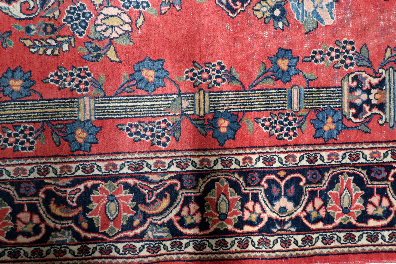 View of the upper section of an antique Persian prayer niche showing the refined Mihrab arch and column capitals.


