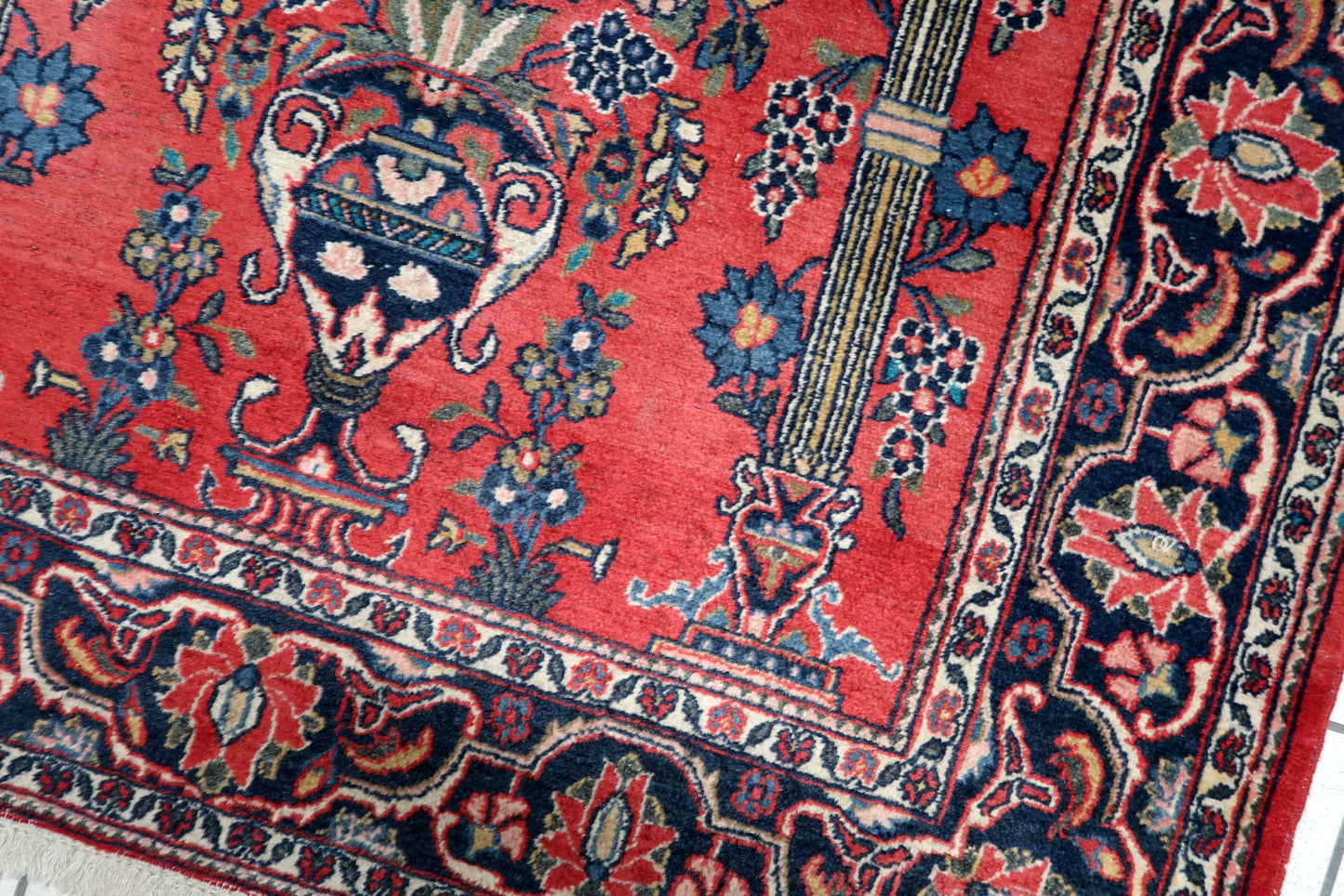Red, midnight blue and ivory antique Persian rug with classical vase motif and symmetrical floral bouquets.
