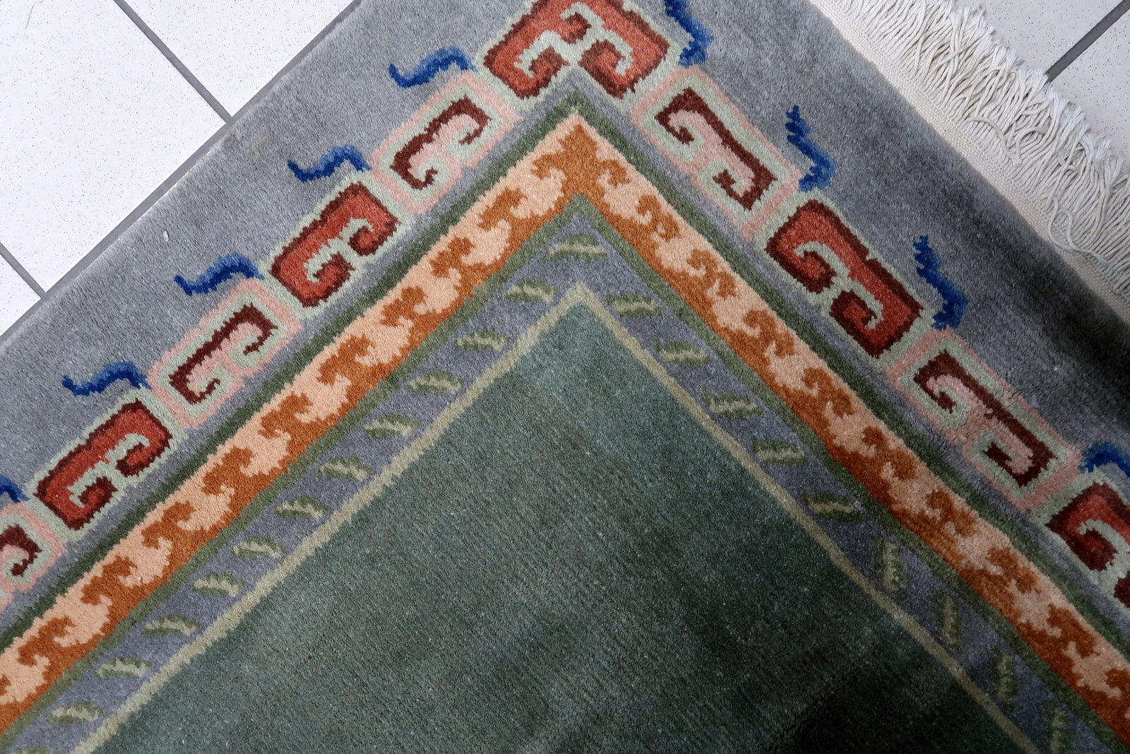 Full view of a vintage Himalayan rug featuring serene moss-green field framed by complex multi-band borders