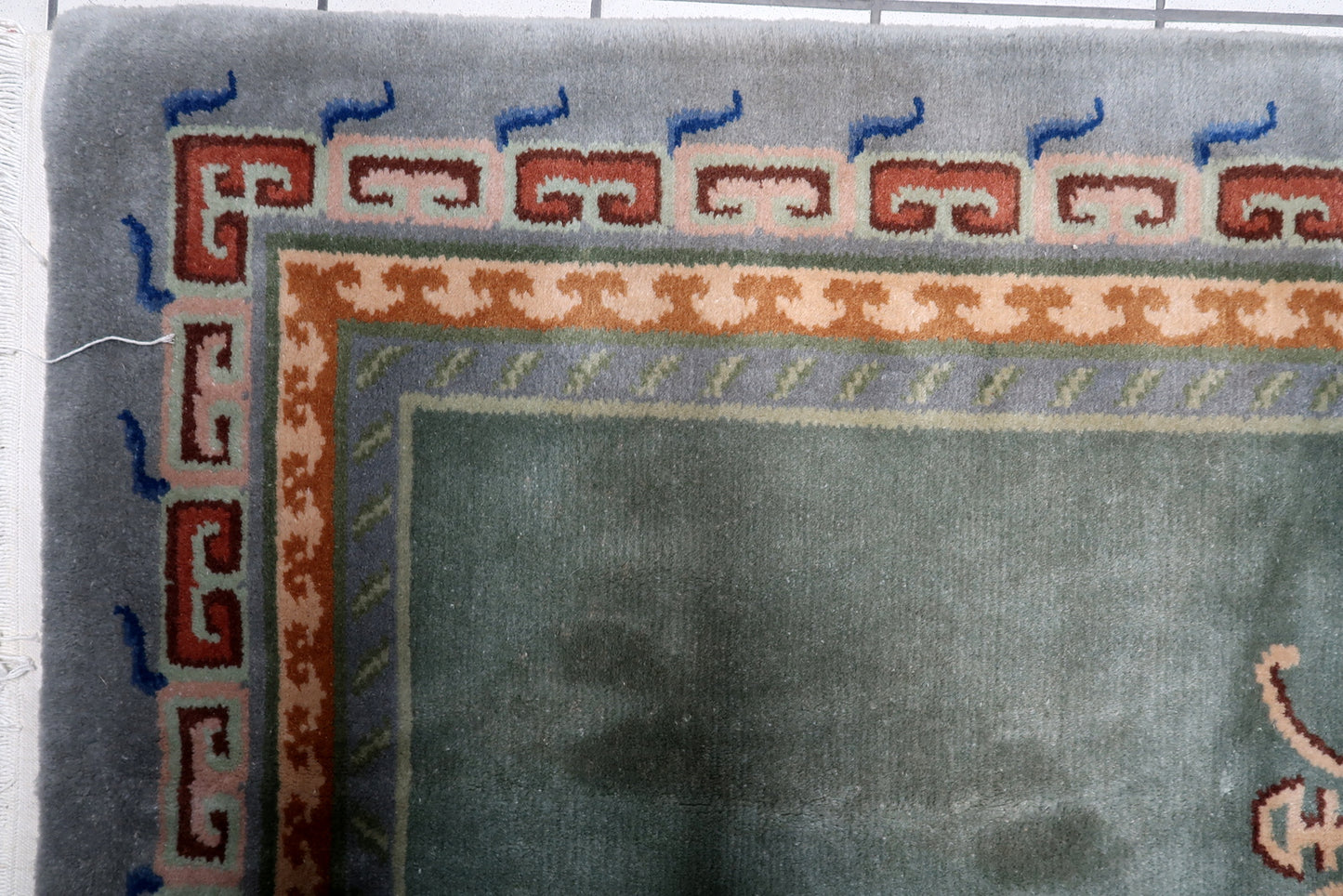 View of the innermost guard border with delicate geometric vine on a vintage Tibetan Art Deco floor covering
