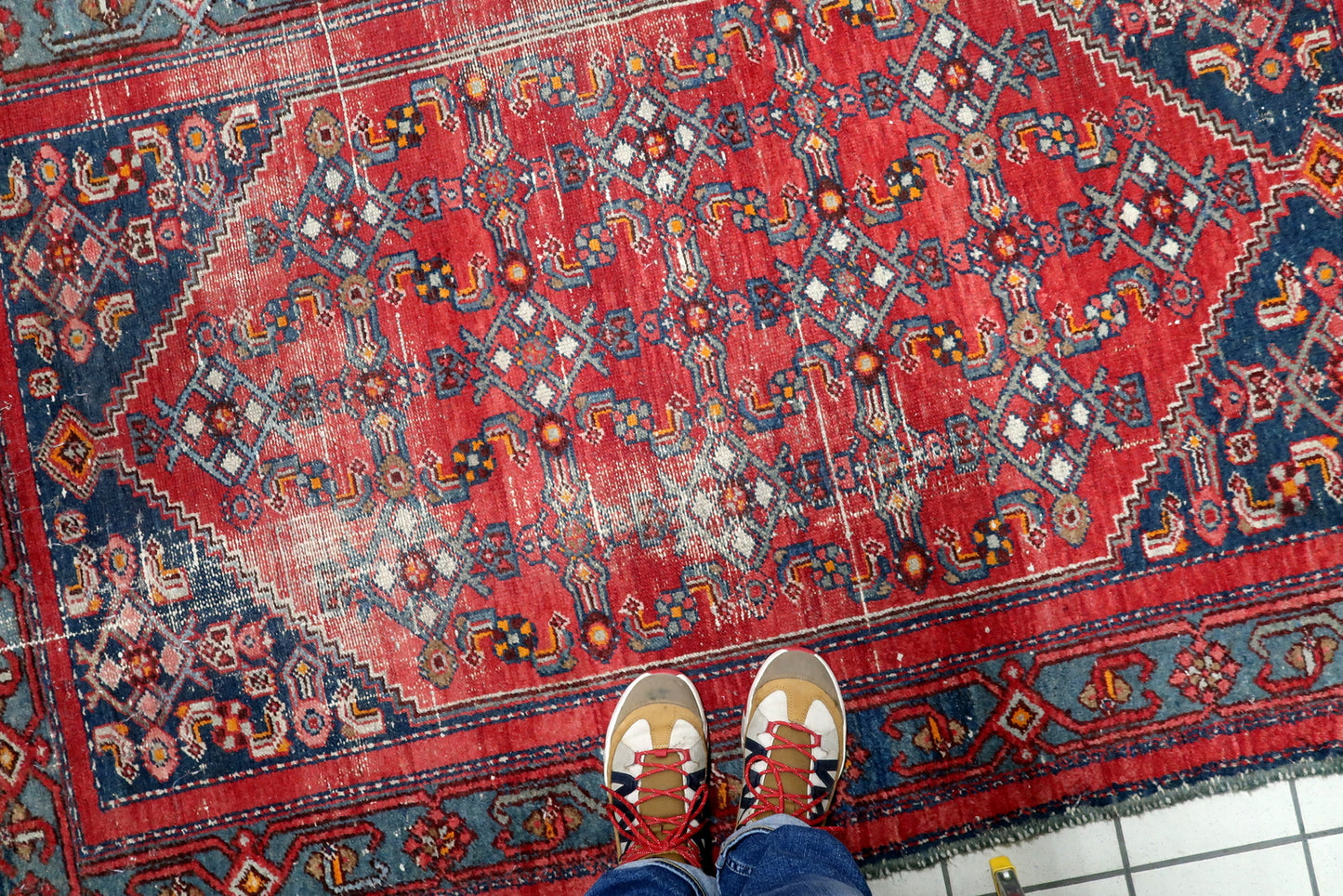 Hand-knotted wool rug in distressed antique condition featuring authentic low pile and visible foundation areas