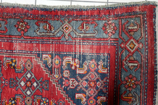 Close-up of traditional tribal motifs and stylized floral rosettes on deep navy blue spandrels of a vintage Persian Hamadan carpet