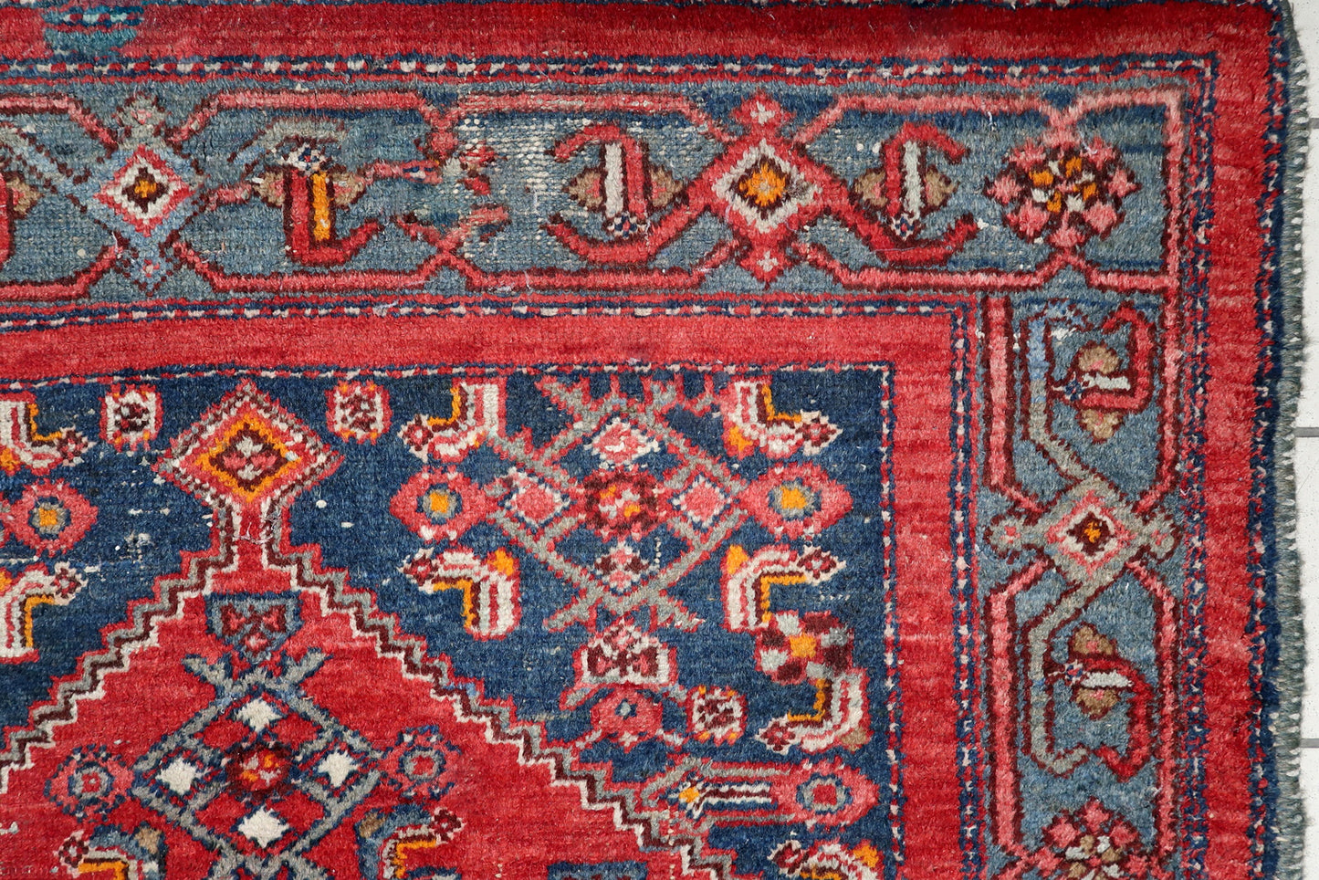 Full view of an antique Persian tribal rug featuring classic geometric medallion and slate-blue borders with intricate details