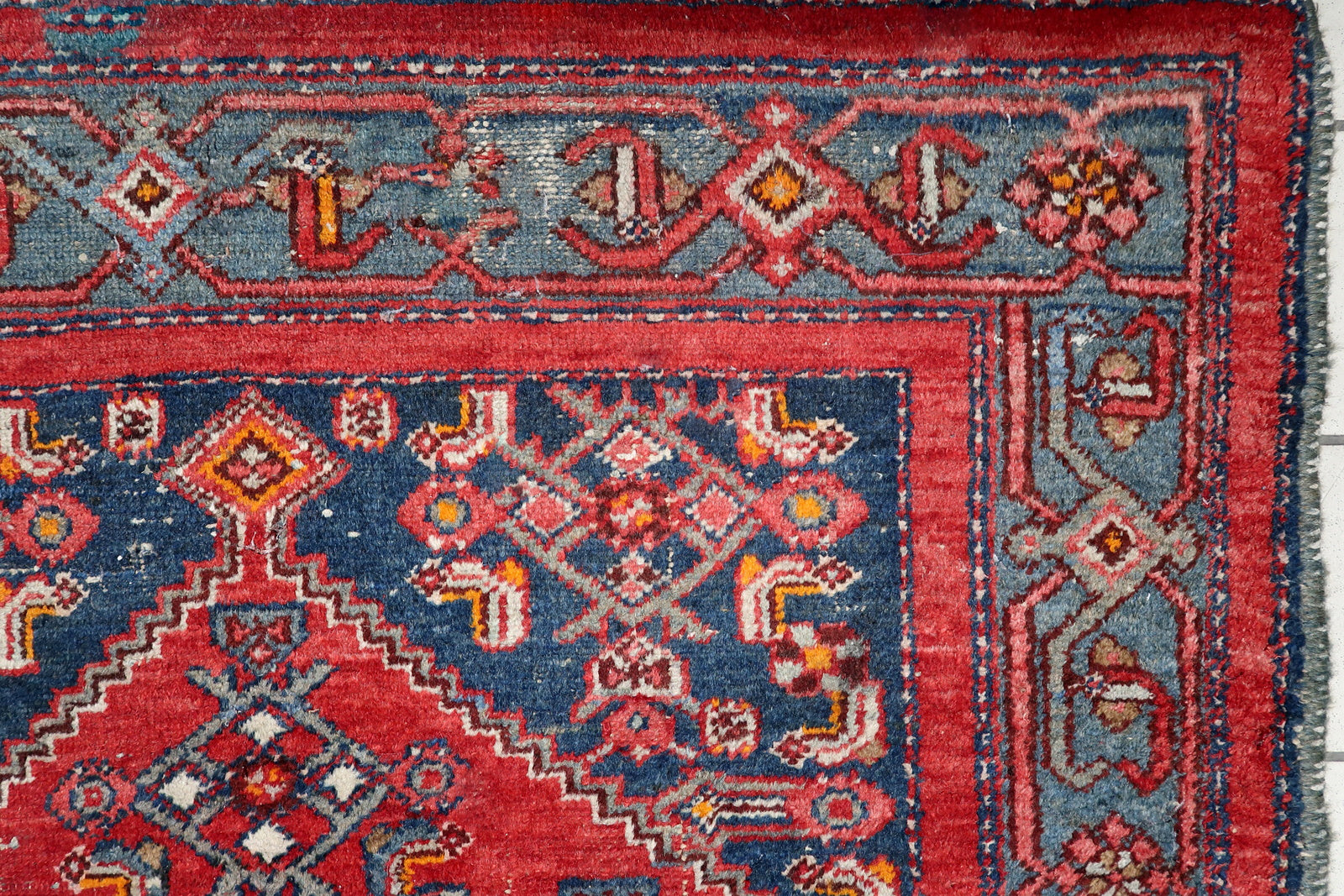 Full view of an antique Persian tribal rug featuring classic geometric medallion and slate-blue borders with intricate details
