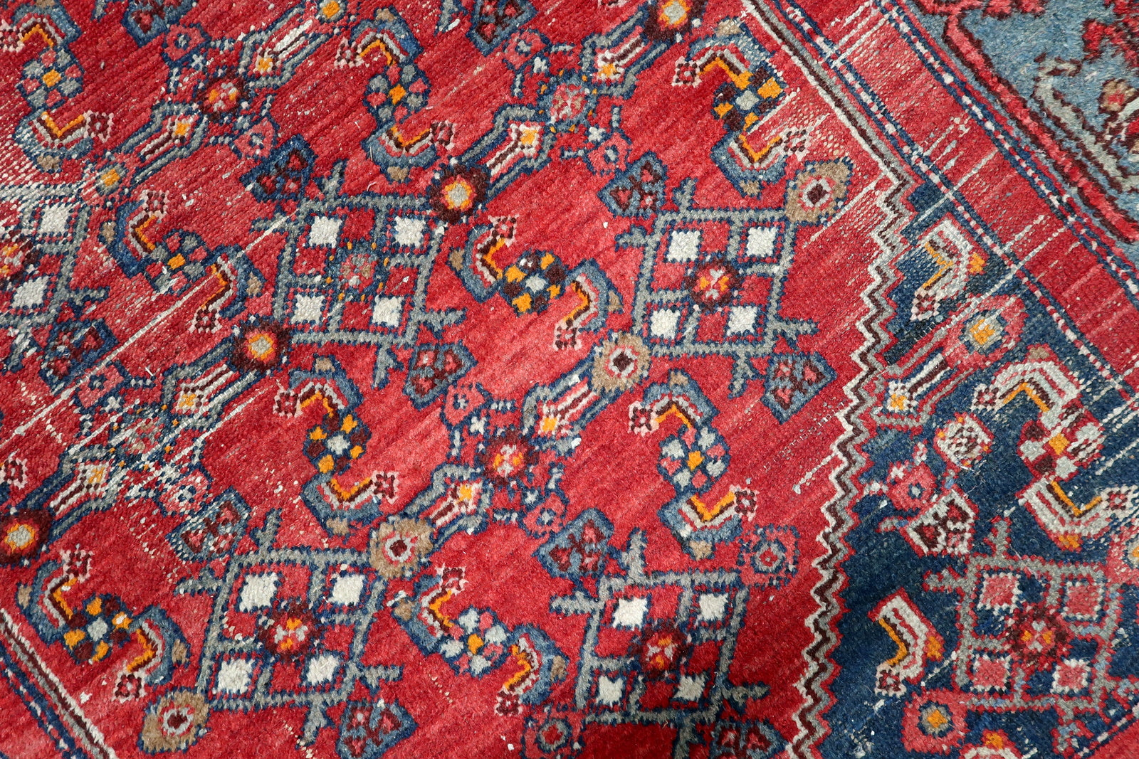 Hand-spun wool texture of a 1920s Hamadan rug with natural abrash color variations and gentle fading from age
