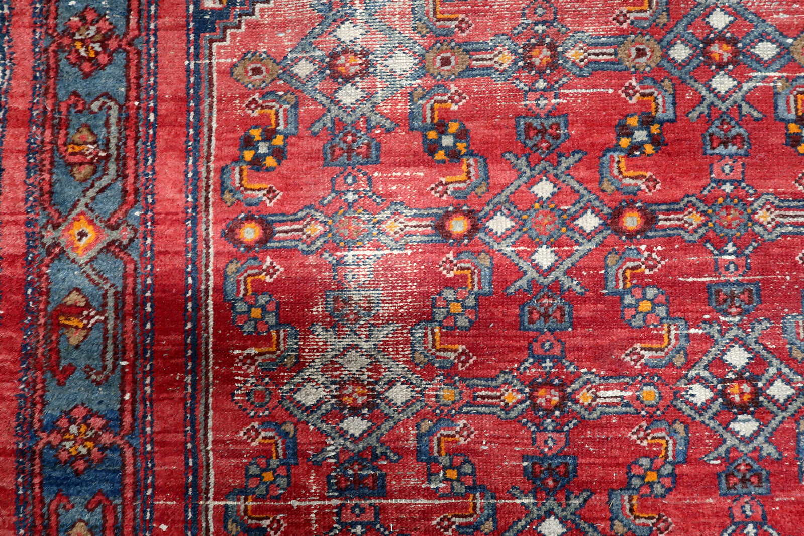 View of slate-blue border with traditional tribal symbols and geometric rosettes on an antique Persian floor covering