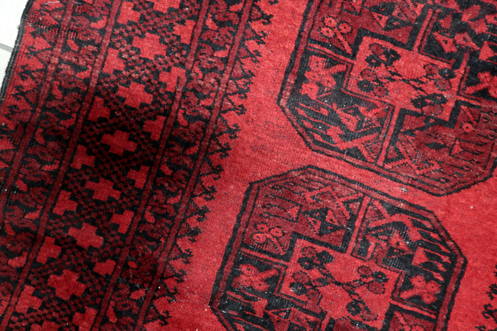 View of traditional elephant foot motifs and geometric star borders on an antique Turkmen tribal floor covering