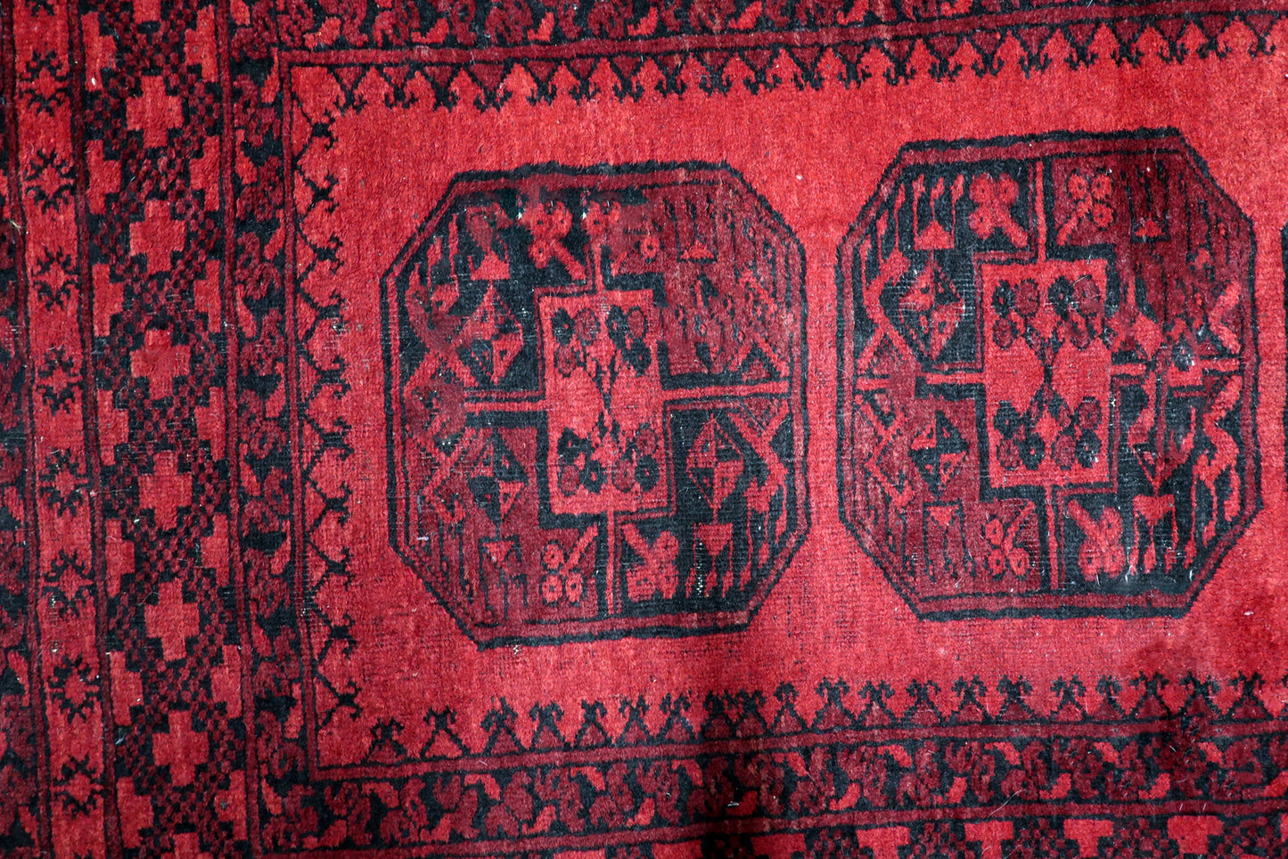 Madder red and midnight black antique Afghan rug with bold architectural guls and dramatic geometric contrast